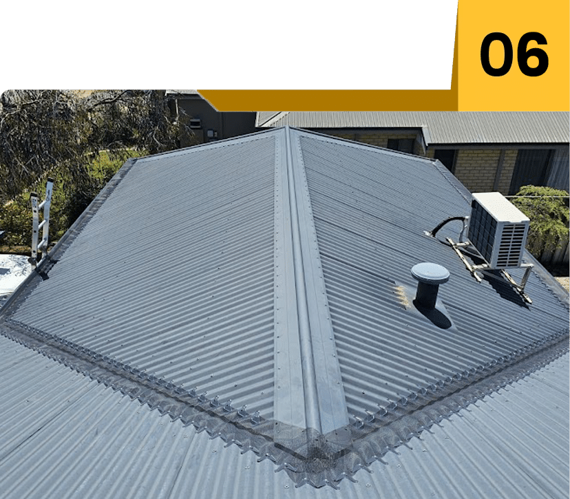 Aerial view of grey metal roof with vent pipe and solar panels.